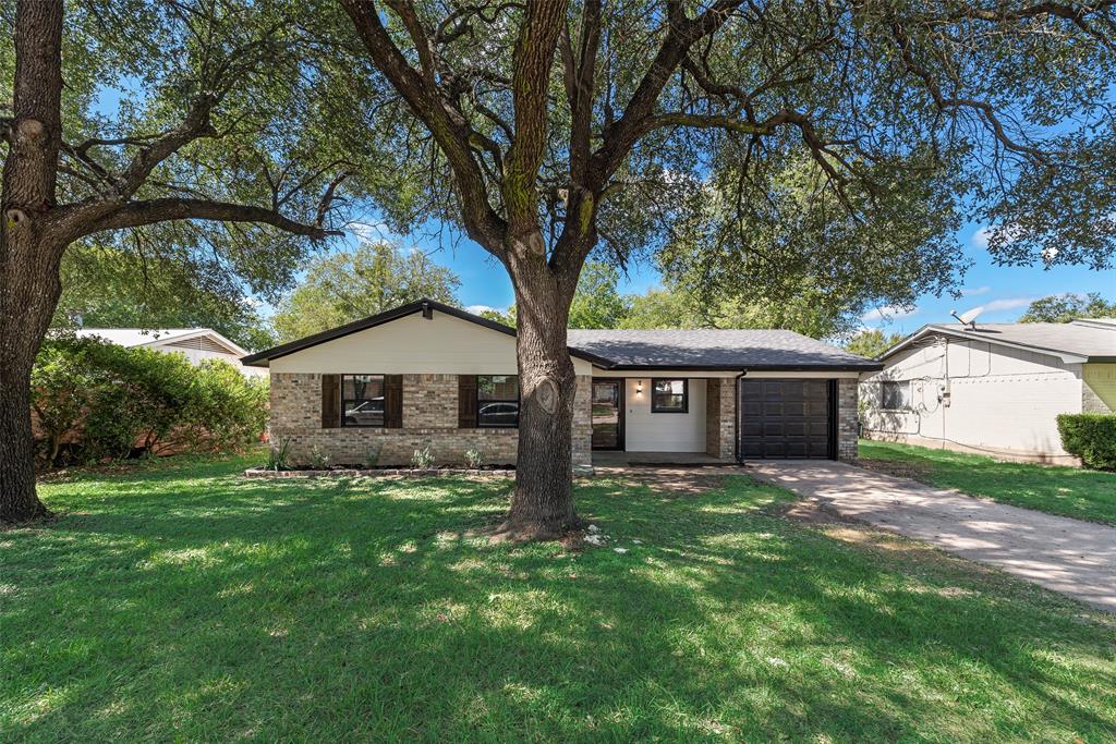 Single-story exterior featuring stone veneer siding, mature shade trees, attached single-car garage, and concrete driveway