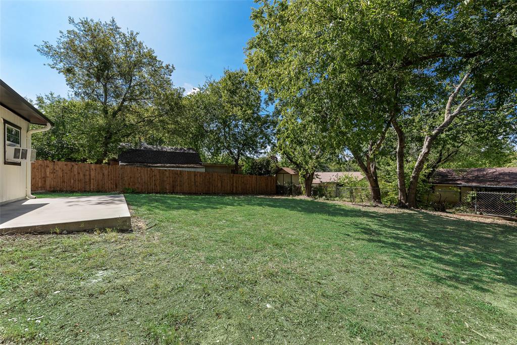 Backyard featuring a concrete patio, wood privacy fencing, and mature trees