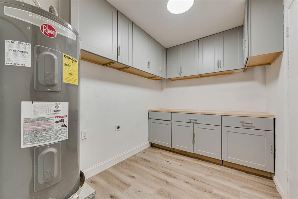 Utility area featuring wood-finish flooring, light grey shaker-style cabinetry, and butcher block countertops