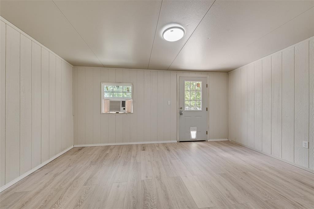 Interior space featuring neutral vertical paneling, wood-finish flooring, a single-lite exterior door, and a flush-mount ceiling light fixture