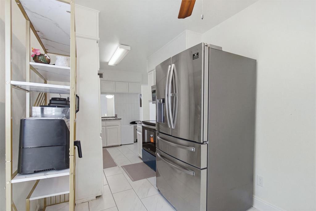 Stainless steel French-door refrigerator, white cabinetry, ceramic tile flooring, and overhead flush-mount lighting
