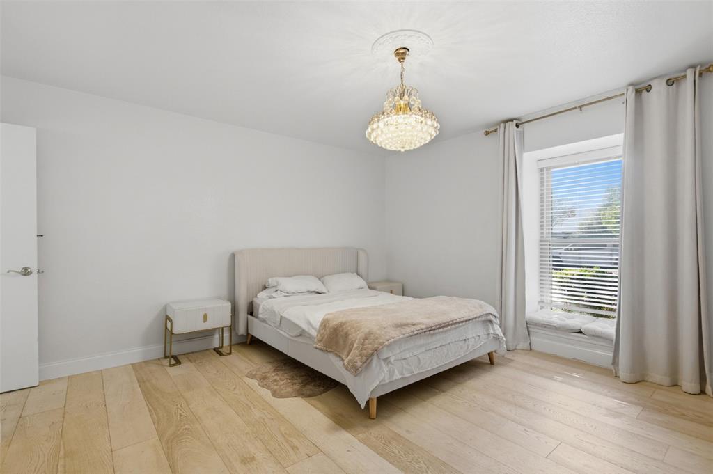 Room featuring wide-plank wood-finish flooring, a recessed window seat, and a decorative crystal chandelier with ceiling medallion