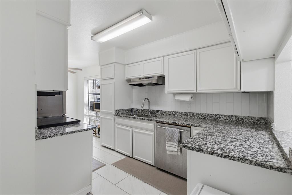 Kitchen featuring white cabinetry, stone-finish countertops, stainless steel dishwasher, subway tile backsplash, and tile flooring