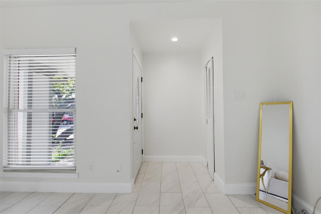 Interior space featuring tile flooring with a neutral-tone finish, single-hung window with horizontal blinds, recessed ceiling lighting, and a louvered bi-fold closet door