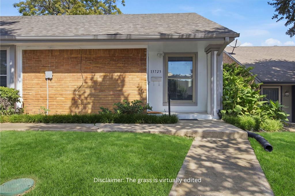 Single-story exterior featuring a brick facade, shingle roof, concrete walkway, and landscaped garden beds