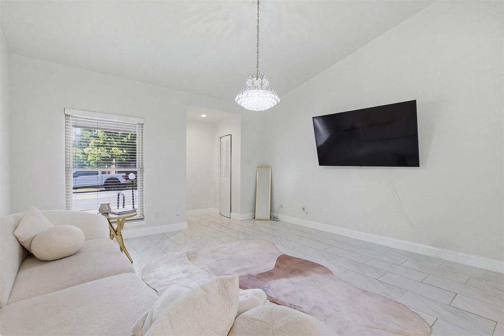 Light-filled interior featuring large-format tile flooring, a multi-tiered crystal chandelier, and neutral wall tones