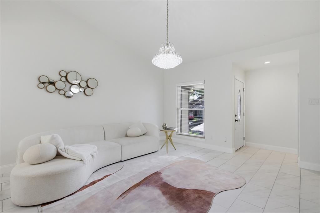 Bright interior space featuring polished tile flooring, a tiered crystal chandelier, and a single-pane window