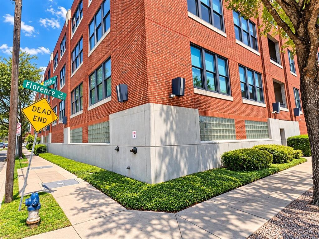 Multi-story red brick exterior featuring a concrete base, glass block masonry, and grid-pattern window groupings Multi-story red brick exterior featuring a concrete base, glass block masonry, and grid-pattern window groupings