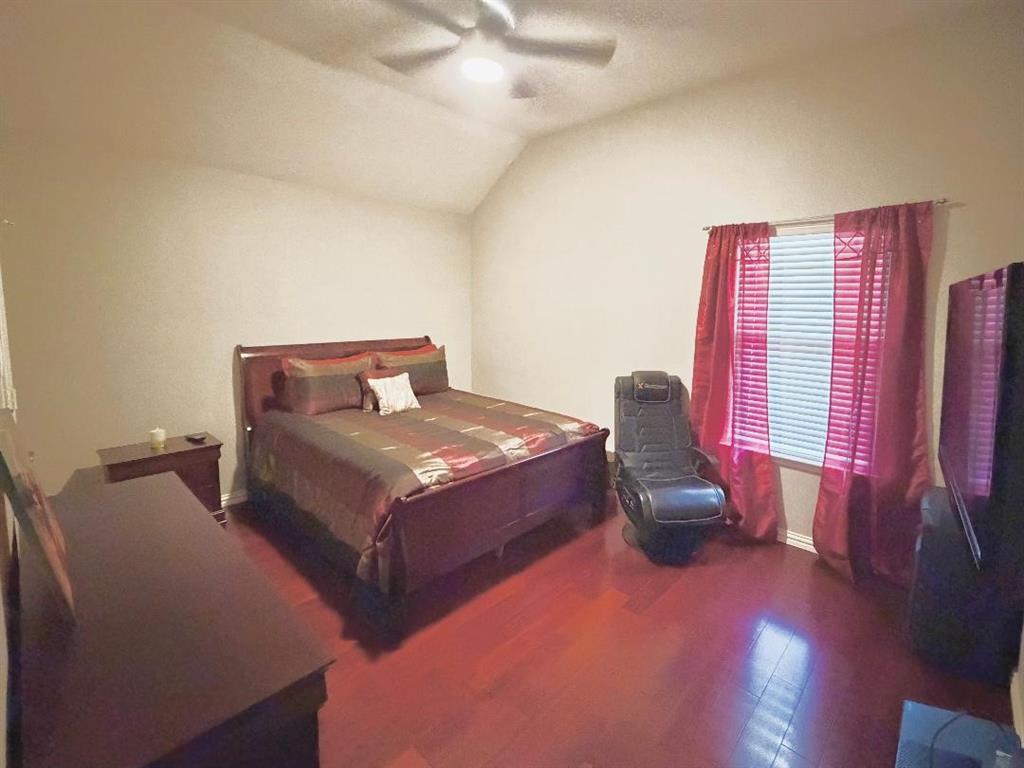 Vaulted ceiling with a centrally mounted ceiling fan and wood-finish flooring