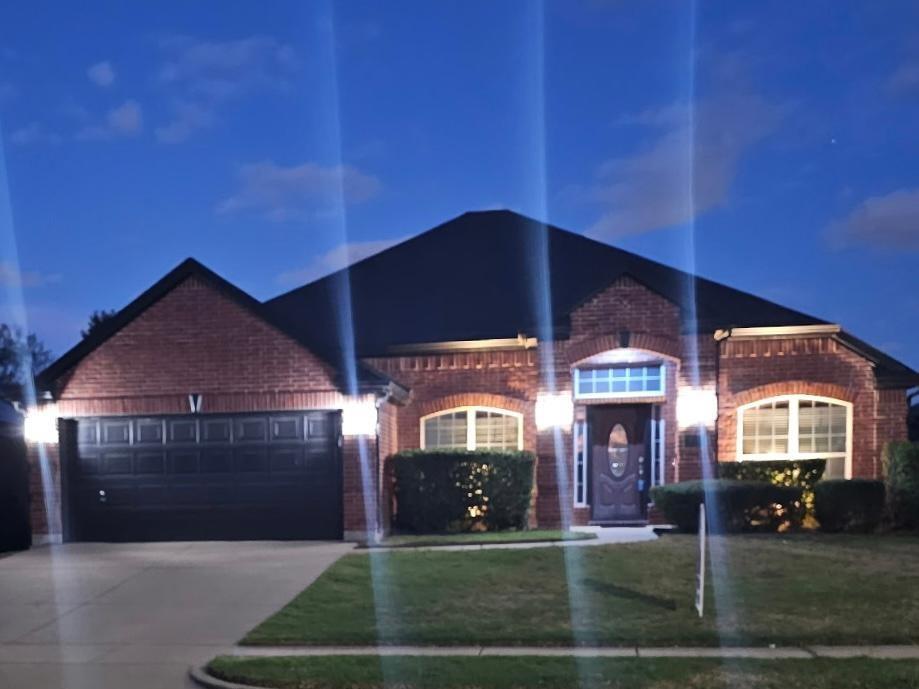 Brick exterior featuring an arched entryway, transom window, multi-paned windows, and a multi-car garage