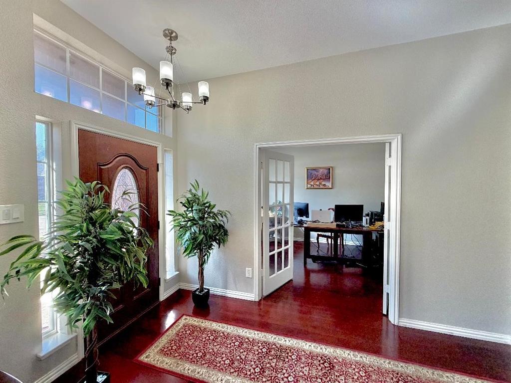 Entryway featuring high ceilings, wood-finish flooring, a multi-pane glass front door with sidelights, a transom window, and white-framed French doors