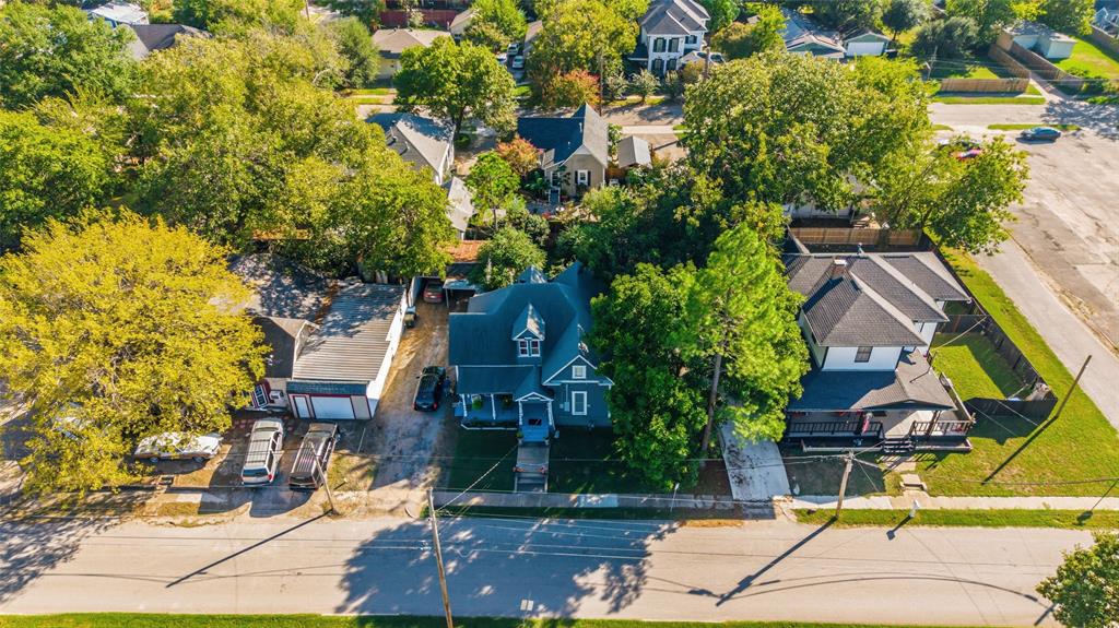 Aerial view featuring mature canopy trees, detached garage structure, asphalt-shingled roof, and paved driveway Aerial view featuring mature canopy trees, detached garage structure, asphalt-shingled roof, and paved driveway