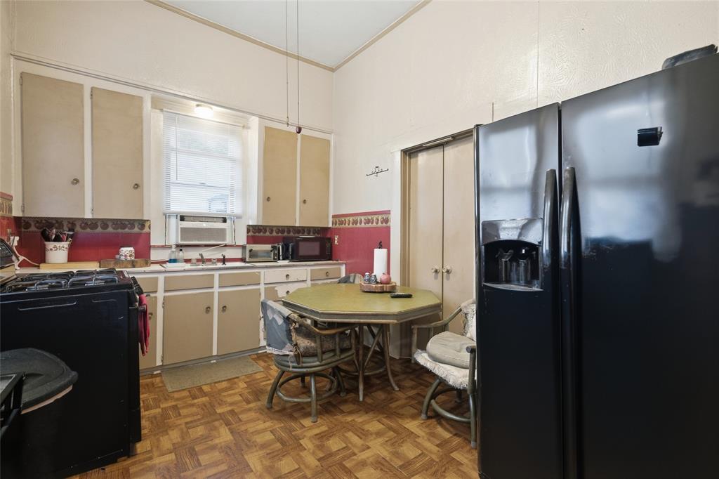 Kitchen featuring parquet flooring, neutral cabinetry, a black side-by-side refrigerator, a black gas range, and a double-door pantry