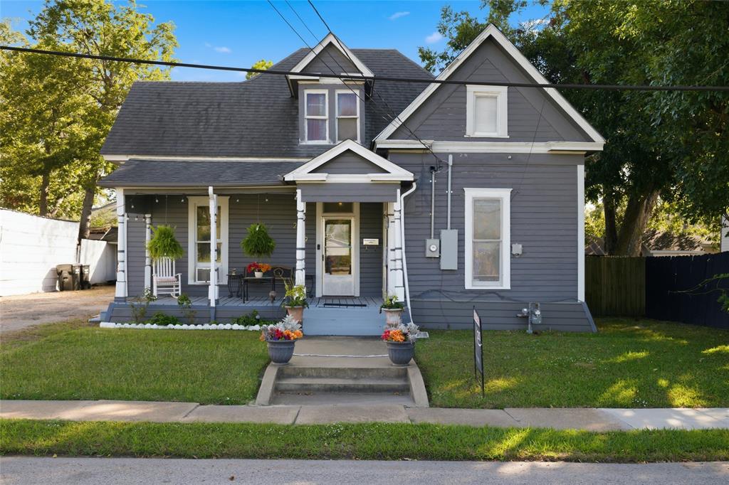 Victorian-style exterior featuring gray horizontal siding, a covered front porch, dual-gabled roofline, and concrete front steps Victorian-style exterior featuring gray horizontal siding, a covered front porch, dual-gabled roofline, and concrete front steps