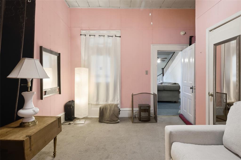 Interior room featuring neutral carpeting, a tiled ceiling, a multi-panel door with metallic hardware, and a tall window with decorative molding