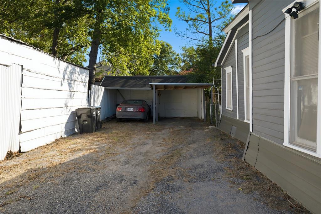Exterior gravel driveway featuring a covered carport and horizontal lap siding