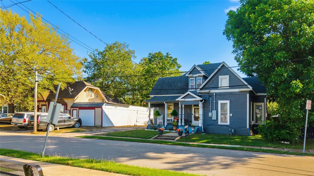 Two-story residence featuring horizontal lap siding, a covered front porch with decorative posts, a cross-gabled roofline, and a detached garage