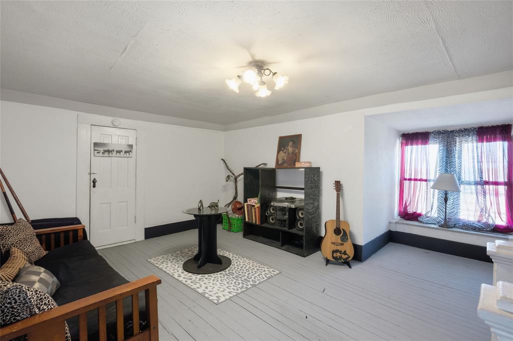 Painted wood-plank flooring, recessed window seat, five-light multi-directional ceiling fixture, and a solid-panel door with vintage hardware