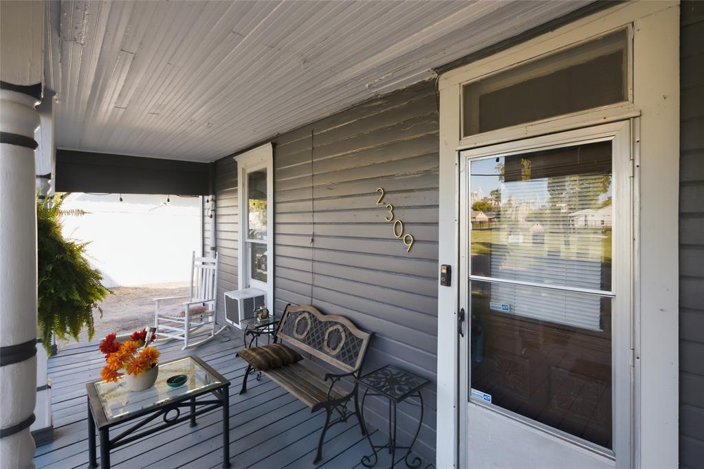 Covered front porch featuring wood-plank flooring, horizontal lap siding, and a transom window above the main entryway Covered front porch featuring wood-plank flooring, horizontal lap siding, and a transom window above the main entryway