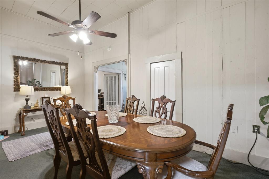 High-ceilinged room featuring vertical wood-plank walls and a multi-blade ceiling fan with integrated lighting