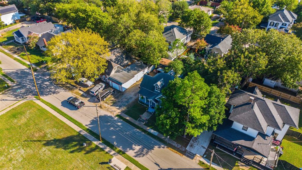 Aerial perspective featuring a multi-story residence with a pitched shingle roof, paved driveway, detached garage structure, and established trees throughout the lot Aerial perspective featuring a multi-story residence with a pitched shingle roof, paved driveway, detached garage structure, and established trees throughout the lot