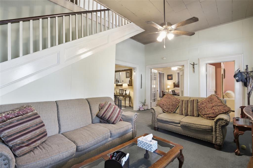 Staircase featuring a white balustrade with a stained wood handrail and recessed paneling, high ceilings, ceiling-mounted fan with integrated lighting, and crown molding