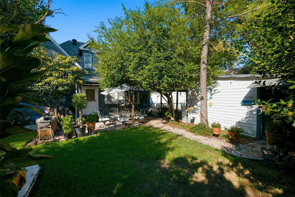 Enclosed backyard featuring a paver patio, mature trees, and a detached white-sided structure