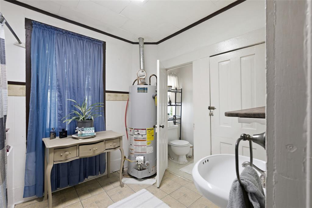 Wall-mounted sink with a metal hardware finish, tile flooring, and integrated water heating unit