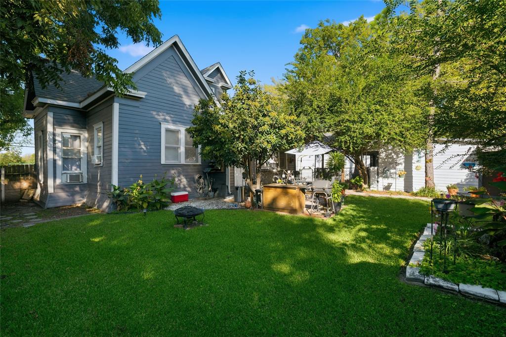Backyard featuring lap siding, manicured lawn, mature trees, and stone-bordered garden beds Backyard featuring lap siding, manicured lawn, mature trees, and stone-bordered garden beds