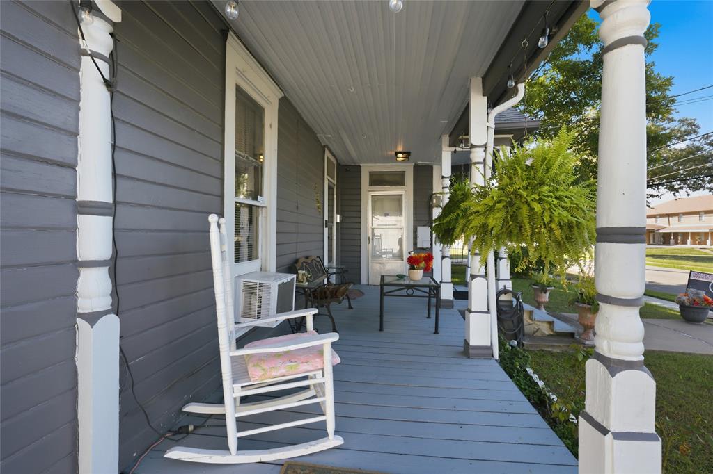 Covered porch featuring dark horizontal siding, decorative white columns, and painted wood-plank flooring Covered porch featuring dark horizontal siding, decorative white columns, and painted wood-plank flooring