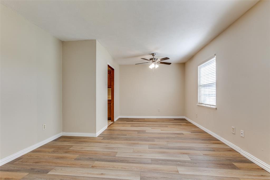 Neutral interior featuring wood-finish flooring, a ceiling fan with integrated lighting, and a window with blinds