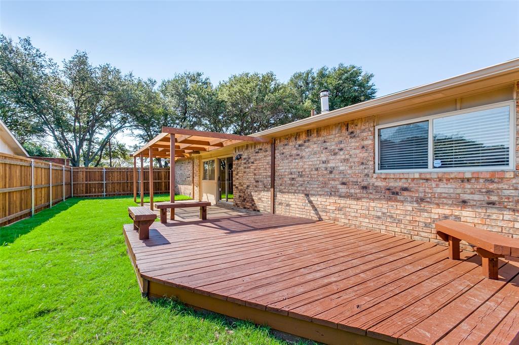 Backyard featuring a multi-level wood deck, built-in wooden bench seating, a wood-frame pergola, brick exterior siding, and a wooden privacy fence