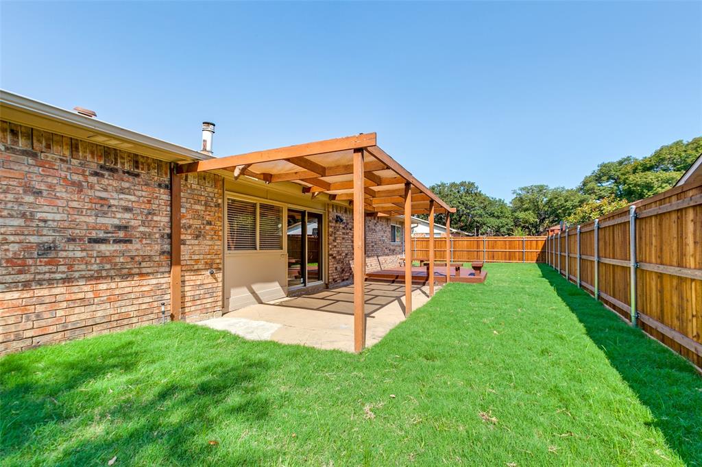 Brick exterior, wood-framed pergola, concrete patio, and perimeter wood fencing