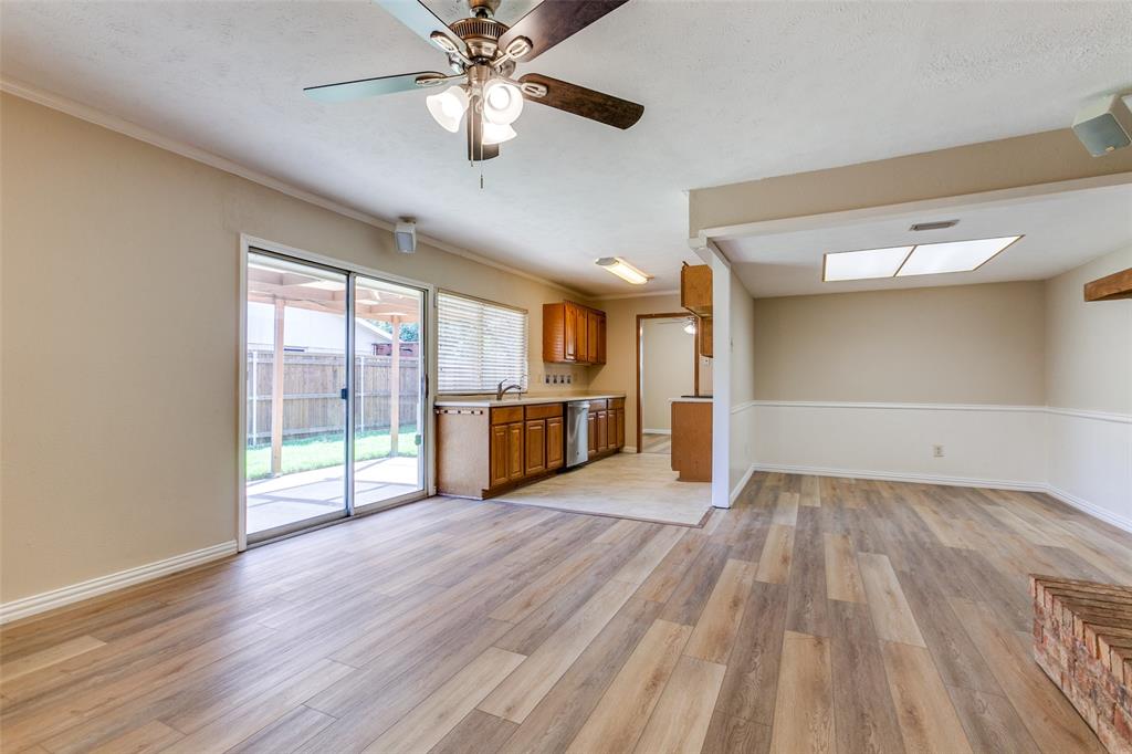 Wood-finish flooring, sliding glass patio door, wooden cabinetry, recessed and ceiling-mounted lighting, and a brick-accented fireplace feature