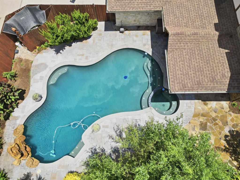Custom freeform pool featuring a built-in spa, stone hardscaping, rock water feature, and flagstone patio