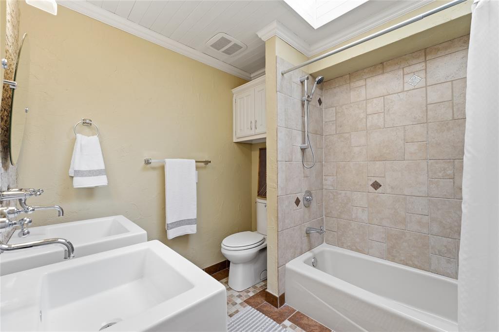 Third bathroom offers tub shower combo and two separate sinks and vanities.