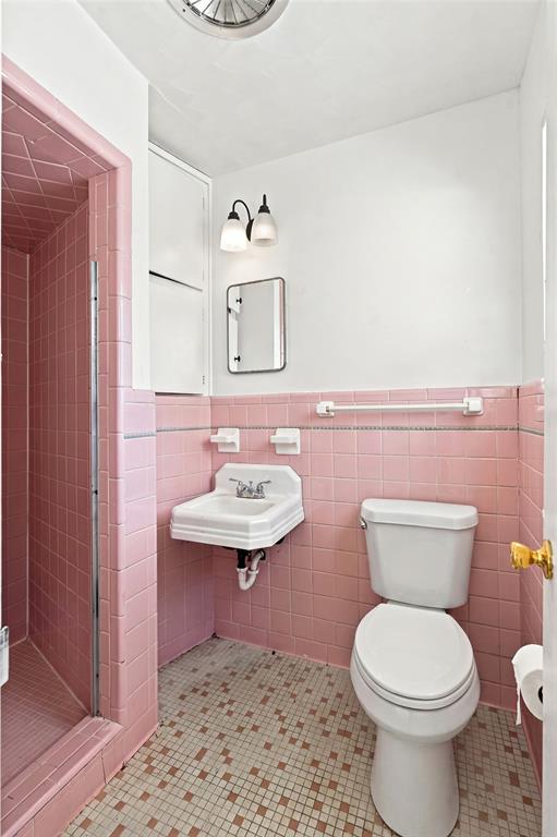 Bathroom featuring pink wall tiling and geometric floor tiling