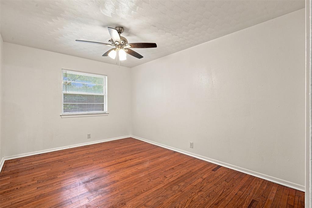 Room featuring wood-finish flooring, a ceiling fan with integrated lighting, and a window with horizontal blinds