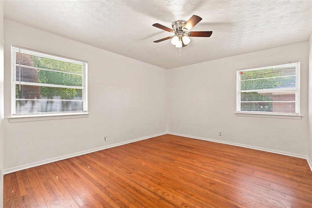Bright interior space featuring wood-finish flooring, white walls, and a ceiling fan with integrated lighting