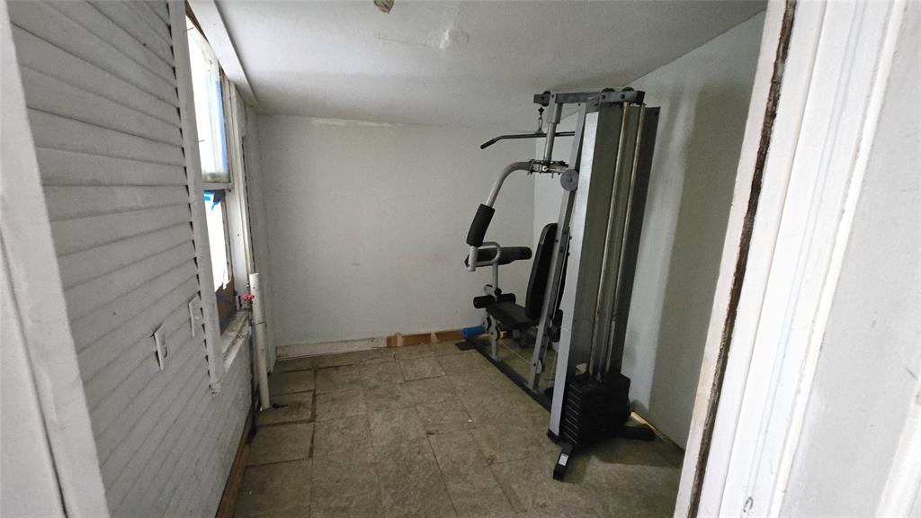 Enclosed space featuring tile flooring, painted wall surfaces, and a multi-pane window with louvered shutter covering Enclosed space featuring tile flooring, painted wall surfaces, and a multi-pane window with louvered shutter covering