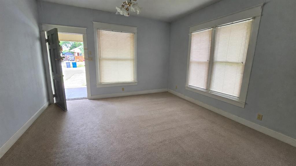 Interior space featuring carpeted flooring, multiple windows with neutral blinds, and an exterior door with architectural trim