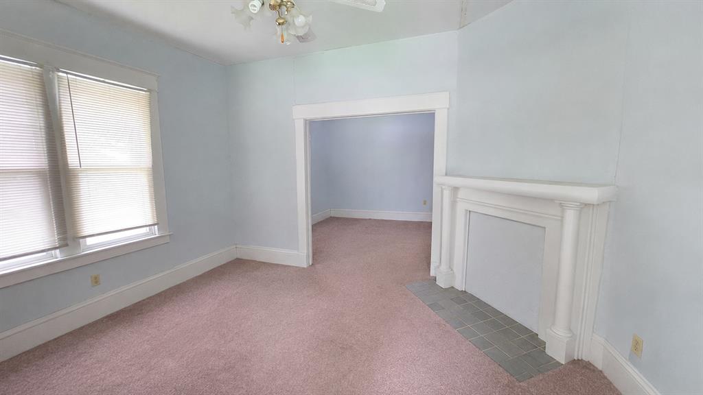 Fireplace featuring a decorative mantel with column detailing and a tiled hearth, framed by wide wood casing and trim Fireplace featuring a decorative mantel with column detailing and a tiled hearth, framed by wide wood casing and trim