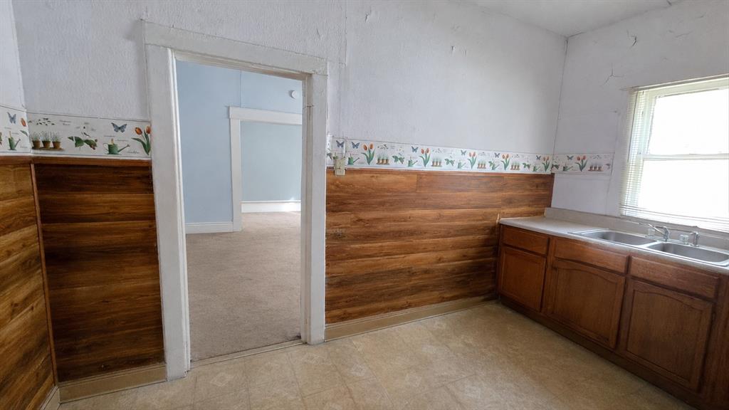 Interior featuring wood-finish wall paneling, floral wall border, cabinetry with integrated double-basin sink, and natural light via a single window