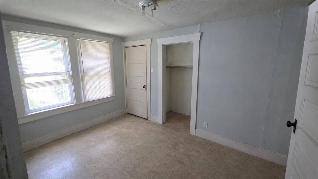 Interior room featuring dual windows with integrated blinds, a closet with shelving, a four-panel door, and a ceiling-mounted light fixture