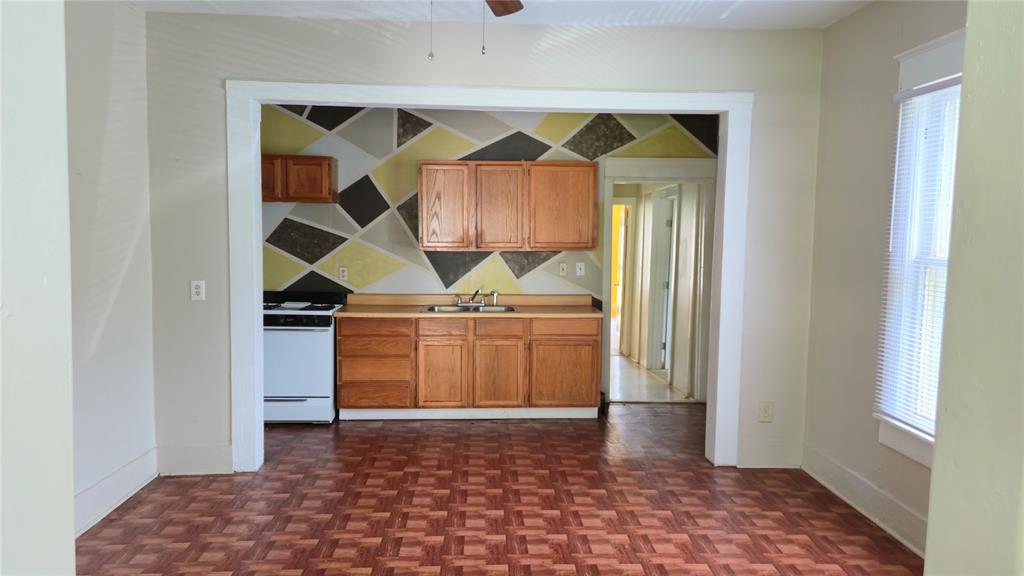 Kitchen featuring wood cabinetry, geometric wall accents, white stove, double-basin sink, and parquet flooring