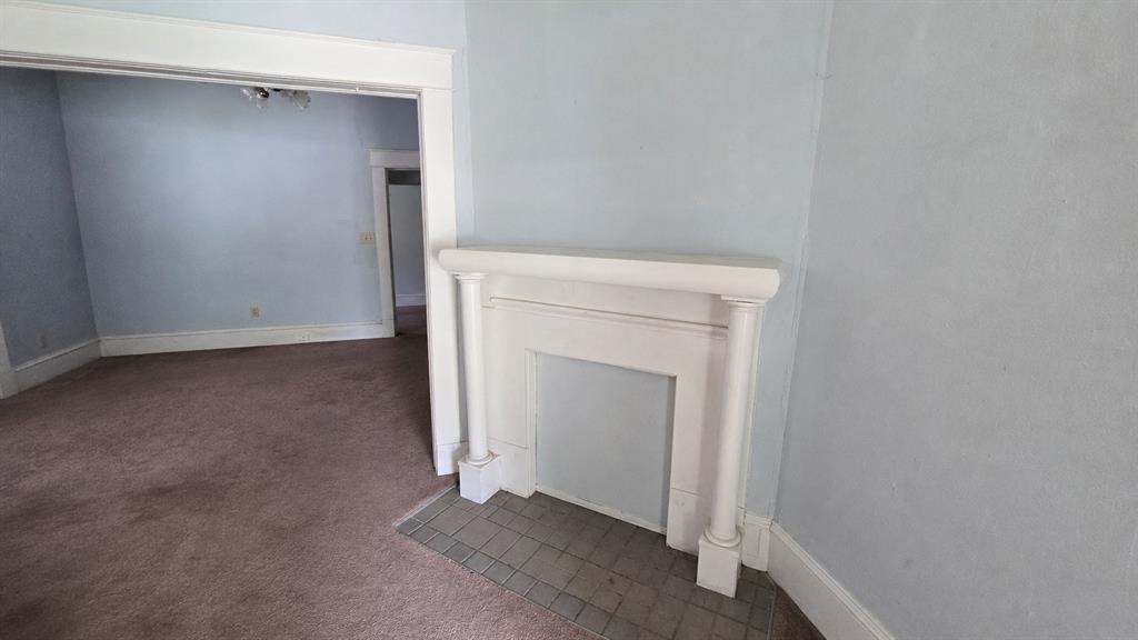 Decorative fireplace mantel featuring fluted columns and a tiled hearth