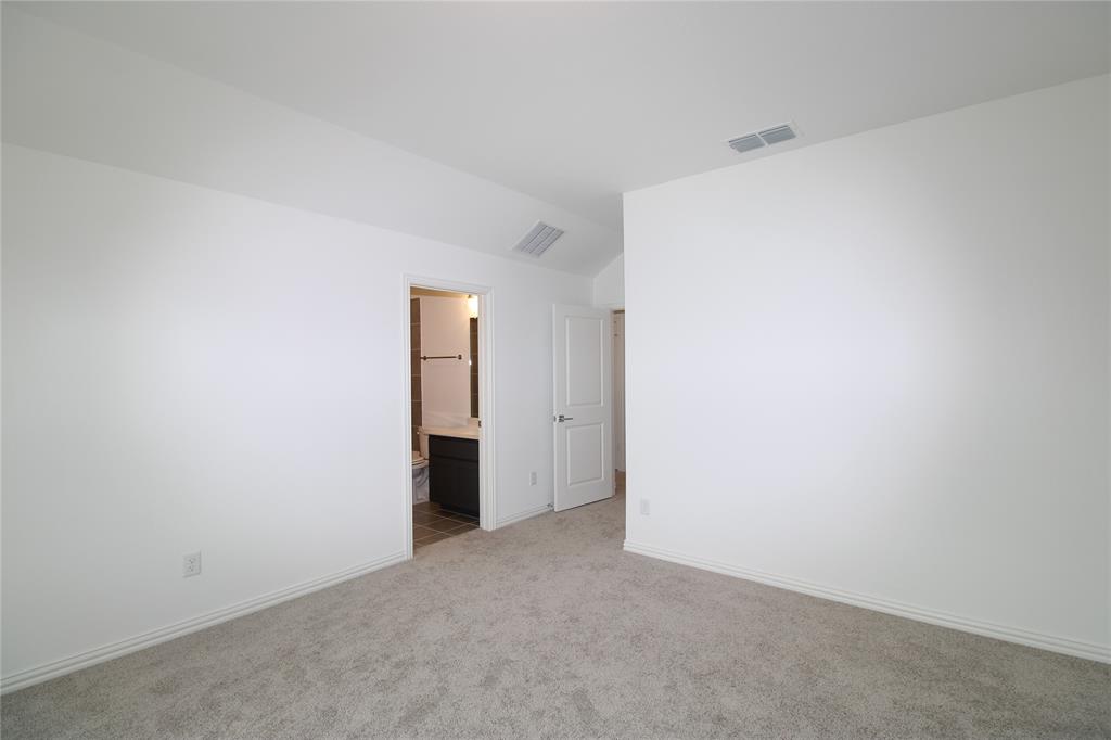 Neutral-toned carpeting, vaulted ceiling, and white interior doors