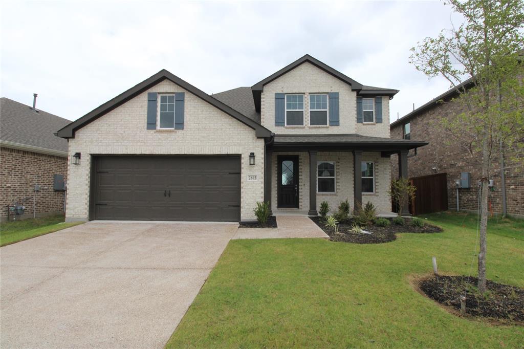 Two-story brick exterior featuring a multi-gabled roofline, front-facing two-car garage, covered entry porch, and decorative shutters