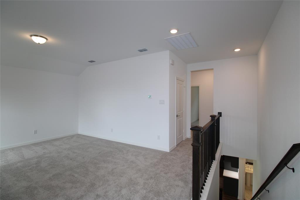 Open-concept loft area featuring neutral wall-to-wall carpeting, recessed lighting, and a dark-finished iron baluster railing