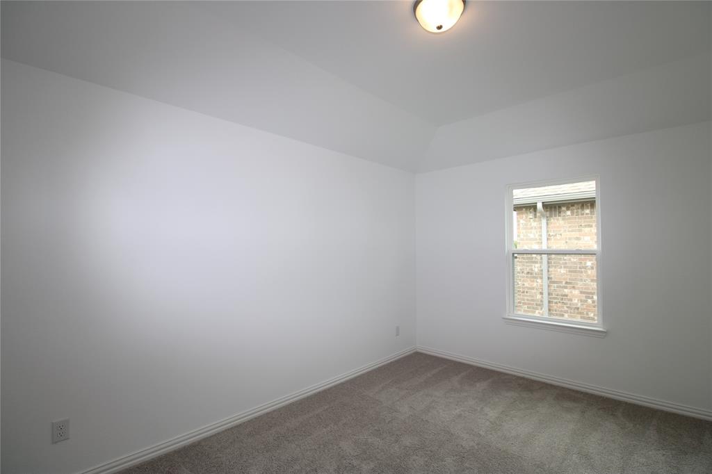 Neutral interior space featuring a vaulted ceiling, wall-to-wall carpeting, and a flush-mount ceiling light fixture